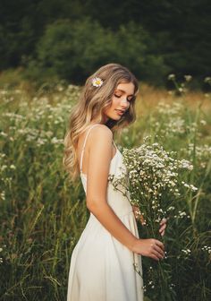 a woman in a white dress standing in tall grass