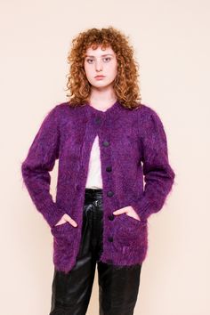 This vibrant knit cardigan features black buttons down the front, two open front pockets in a super soft fuzzy purple wool blend. Measurements: Bust 42", Waist 36", Length 30" Material: 78% Mohair, 13% wool, 9% Nylon Brand: Anncraft Care: Hand wash, dry flat Condition: Excellent Purple Soft Knit Outerwear For Fall, Fitted Purple Cardigan For Fall, Purple Long Sleeve Cardigan For Winter, Soft Knit Purple Outerwear For Fall, Purple Buttoned Sweater For Fall, Purple Long Sleeve Sweater Coat For Fall, Purple Button Sweater For Fall, Purple Fitted Cardigan For Fall, Purple Buttoned Sweater For Winter