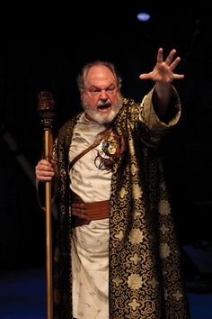 a man dressed in medieval clothing holding a staff