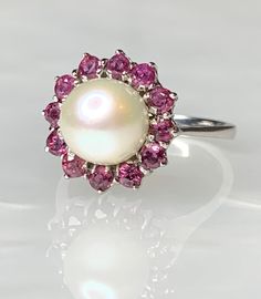 "Vintage Pearl Ring For Women, Vintage Pearl Ring, Pearl Engagement Ring, One of a Kind Pearl Ring, Pearl Gold Ring, \"Pearl in a box\", OOAK An exquisite and timeless ring featuring a genuine pearl surrounded by a halo of sparkling rubies weighing 1.00 carat, set in solid 18k white gold. * Ring size: US 7 * Complimentary resizing is available up to 3 sizes larger or smaller than stated size. * The ideal gift for life's milestones: Engagement Ring, Birthday Gift, Valentine's Day or Mother's Day" White Pearl Ring With Center Stone, White Round Ruby Ring Fine Jewelry, White Round Ruby Ring In Fine Jewelry Style, White Pearl Birthstone Ring Fine Jewelry, White Pearl Birthstone Ring In Fine Jewelry, White Fine Jewelry Round Ruby Ring, Fine Jewelry White Pearl Birthstone Ring, White Pearl Birthstone Ring, White Cluster Rings Hallmarked