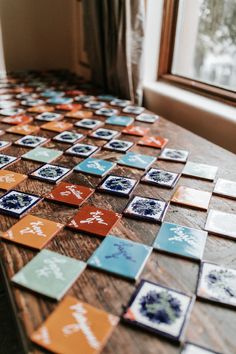 a wooden table topped with lots of different colored tile tiles on top of each other