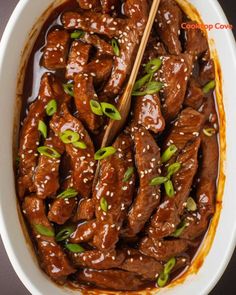 beef with sesame seeds and green onions in a white bowl on a table top, ready to be eaten