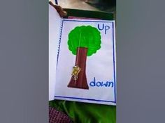 a child holding up a sign with a tree on it that says, up down