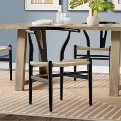 a dining room table with two chairs and a potted plant