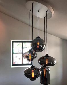 three lights hanging from the ceiling in a room with white walls and windows behind them