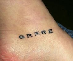 the word grace written in small black ink on a person's foot with an arrow