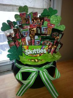 a st patrick's day candy arrangement in a black pot with green ribbon and shamrock decorations