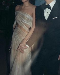 a woman in a white dress and a man in a tuxedo are standing next to each other