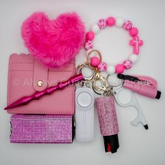 a pink purse, keychain, and other items are arranged on a white surface