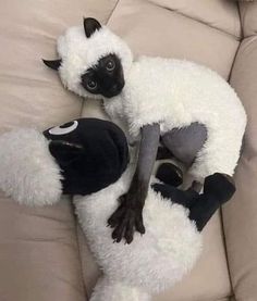 two stuffed animals laying on top of a couch next to each other in the shape of sheeps