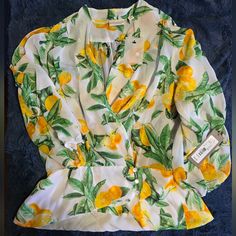 This Stunning Blouse By New York & Company, Designed By Eva Mendes, Is Perfect For Any Woman Looking To Add A Touch Of Sophistication To Her Wardrobe. The Citrus Pattern And White Color Make It A Versatile Piece That Can Be Dressed Up Or Down For Any Occasion. The Blouse Features Beautiful Button Accents And A Flattering Wrap Style, Making It A Perfect Choice For Any Fashion-Forward Woman. Constructed With High-Quality Materials, This Blouse Is Sure To Last For Years To Come. It Is Available In Citrus Pattern, Eva Mendes, Woman Looking, New York And Company, Wrap Top, Wrap Style, White Color, Fashion Forward, Womens Tops