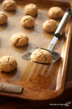 a cookie sheet with cookies on it and a spatula next to the doughnuts