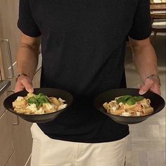 a man holding two black plates filled with food