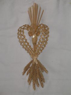 a decorative piece made out of straw and beads on a white background with a cross in the middle