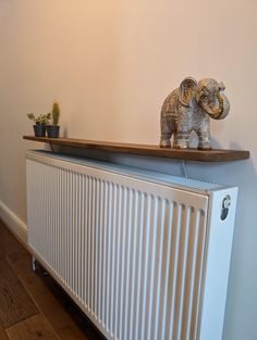 an elephant figurine sitting on top of a radiator next to a potted plant