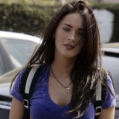 a young woman walking down the street with her hand in her pocket and wearing a blue shirt