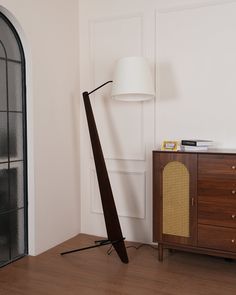 a lamp that is sitting on top of a wooden floor next to a cabinet and door