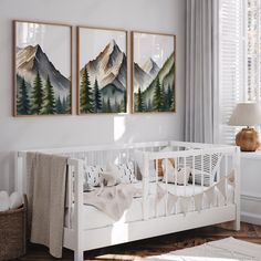 a white crib with two paintings on the wall