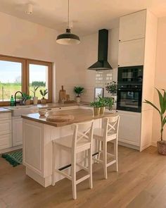 a kitchen with white cabinets and wooden flooring next to an open doored window