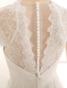 the back of a wedding dress with white lace and pearls on the bouncy