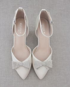 a pair of white shoes with bows on the toes and heels are shown in front of a gray background