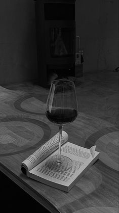 a glass of wine sitting on top of an open book