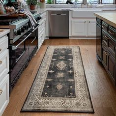 a kitchen with an area rug on the floor next to the stove and dishwasher