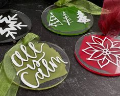 three christmas ornaments with ribbons on them sitting on a table next to some paper decorations