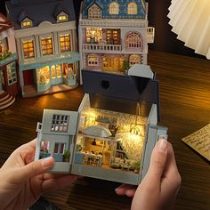 someone is holding a doll house in their hands