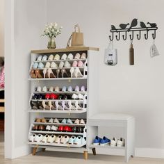 a shoe rack with several pairs of shoes on it in a living room next to a white bench