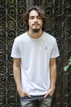 a man standing in front of a gate with his hands in his pockets and looking at the camera