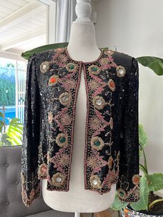 Stunning, sequin, evening jacket with heavy gold embroidery and black beading. Jacket is fully lined and has shoulder pads that could be removed with one hook and eye closure in the front. In overall excellent vintage condition with no notable flaws, no holes, snags, stains, or missing beads or sequins, however there are loose gold threads near the top of the shoulders. Tag reads Suzette International, Paris, Santa Fe, would best fit a size small. Measurements Chest 38in/96.5cm Length 20in/51cm Shoulders 15in/38cm Sleeve 23in/28cm *Please keep in mind that unless otherwise noted, all items in my shop are used or previously owned, normal wear and tear is expected, flaws that are noted are range from major to minor, things like a missing stitch here or there my not be included. *Please read Diane Freis, Evening Jacket, Womens Jackets, Evening Jackets, Gold Embroidery, Gold Threads, Blue Suede, Little Miss, Vintage Sweaters