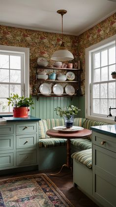 a kitchen with green cabinets and floral wallpaper on the walls, along with a round dining table