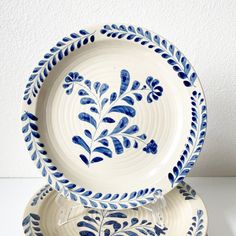 three blue and white plates stacked on top of each other, with leaves painted on them