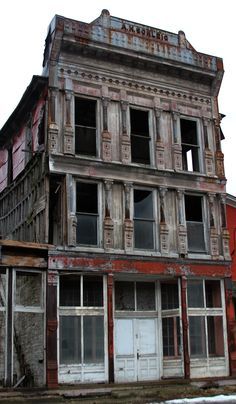 an old run down building with broken windows and shutters on the second floor is shown