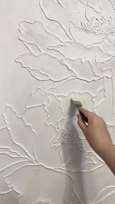 someone is using a brush to paint flowers on a white wall with acrylic