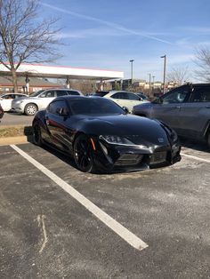 two black sports cars parked in a parking lot next to each other on a sunny day