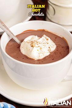 a white bowl filled with chocolate and whipped cream on top of a plate next to a spoon