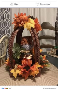 an owl figurine sitting on top of a basket filled with flowers and leaves