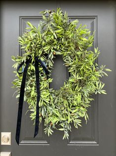 a green wreath with black ribbon hanging on a door