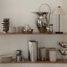 the shelves are full of silver dishes and cups on them, along with a lamp