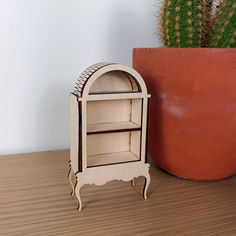 a small wooden shelf next to a potted cactus