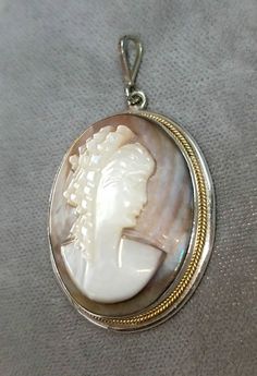 Hallmarked 800 silver Mother of Pearl cameo pendant. The cameo pendant measures approximately 1 1/2 inches x 1 inch. The necklace chain attached to the cameo pendant is sold separately. Other necklace styles are also available. The cameo pendant is in very good condition. The cameo pendant is circa 1940. The cameo pendant comes in a quality gift box. Cameo Medallion Jewelry For Anniversary, Silver Cameo Medallion Necklace, Silver Cameo Pendant Necklace, Silver Cameo Round Pendant Jewelry, Collectible Cameo Jewelry With Round Pendant, Silver Cameo Jewelry With Round Pendant, Round Silver Cameo Necklace, Collectible Cameo Round Pendant Jewelry, Silver Cameo Round Jewelry