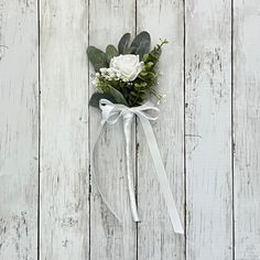 a boutonniere with white flowers and greenery tied to it on a wooden surface