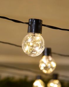 several light bulbs are hanging from a string in an indoor area that is decorated with christmas lights