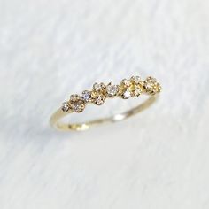 a yellow gold ring with five diamonds on the top and bottom, sitting on a white surface