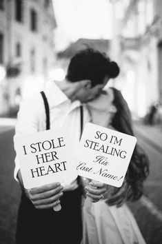 a couple kissing while holding signs that say i stole her heart and som stealing the last name