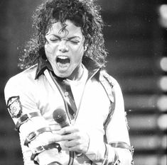 michael jackson singing into a microphone while holding his hands in his pockets and mouth open