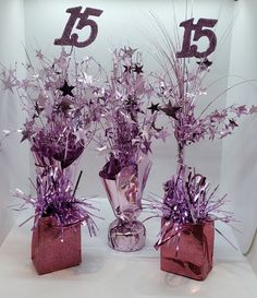 three vases filled with purple flowers on top of a white table covered in glitter