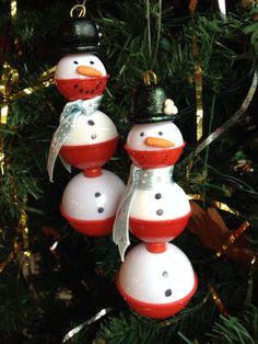 three snowman ornaments hanging from a christmas tree